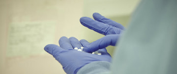 A person with gloves sorting pills in their hands