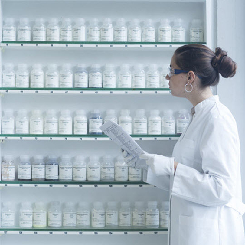 Pharmacist looking at pills on shelves.